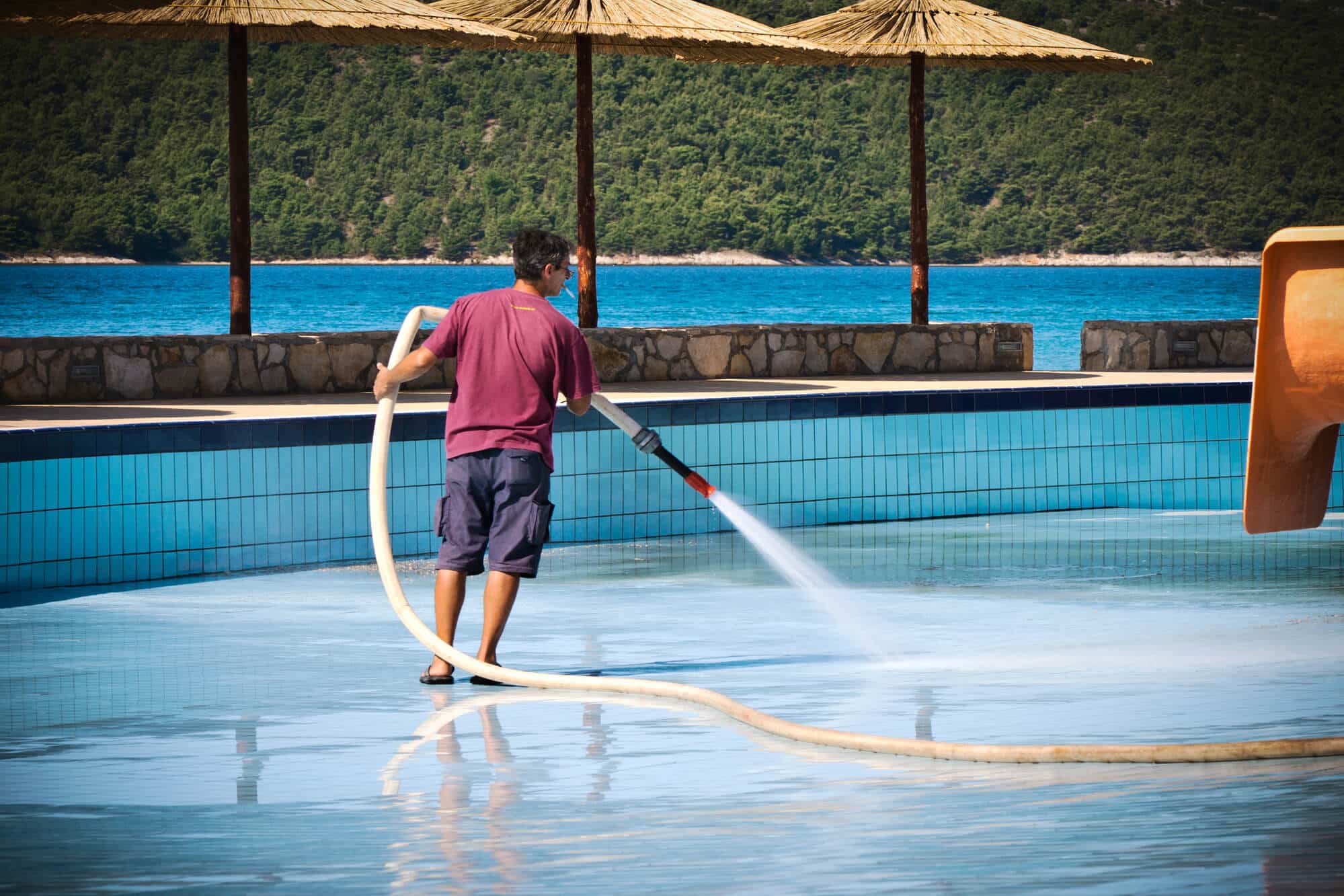man pressure washing pool