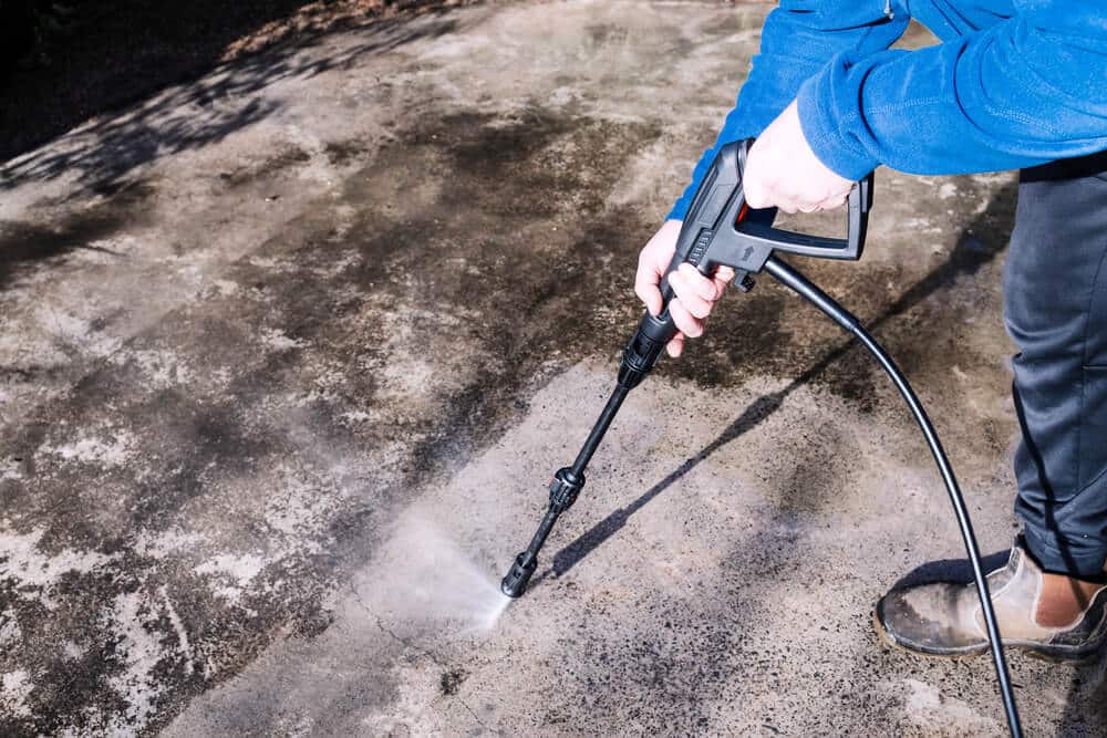 Worker in hi-vis washing a paved surface